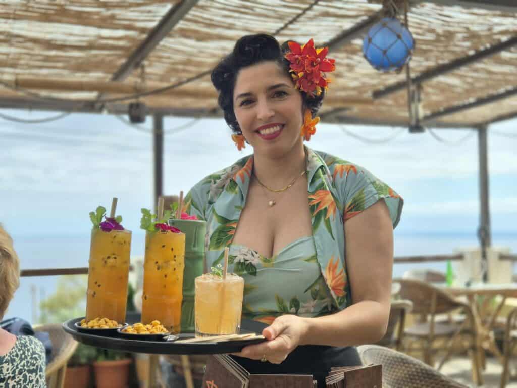Serveerster met bloem in haar haar, met drie rumcocktails op haar dienblad bij de Pukiki bar op Madeira
