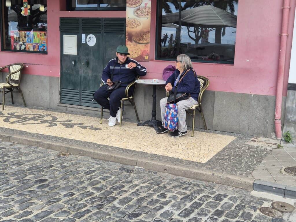 Twee locals genieten van koffie op een terrasje in een klein dorp op Madeira – een typisch straatbeeld dat de ontspannen sfeer en charme van de Madeirese dorpen weerspiegelt. Kleine dorpen op Madeira
